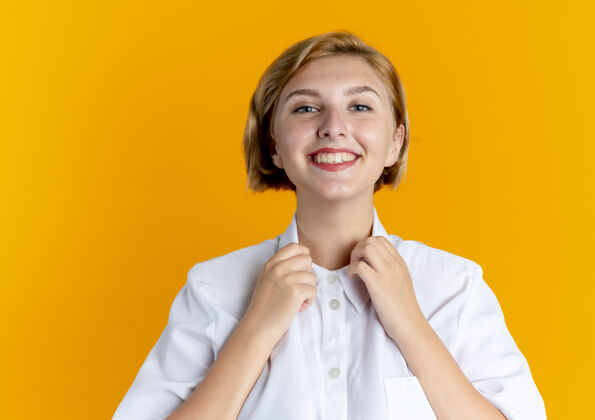 金发年轻的微笑金发俄罗斯女孩举行孤立的橙色背景与复制空间衣领女孩微笑领子
