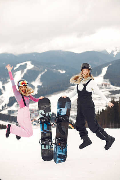 年轻人穿着滑雪板套装的女人在山上的运动员手拿滑雪板在地平线上关于运动的概念护目镜木板娱乐
