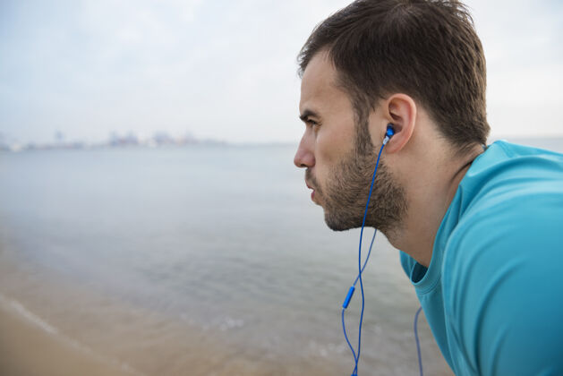 帅气特写在海边慢跑的健康年轻人运动员努力运动训练