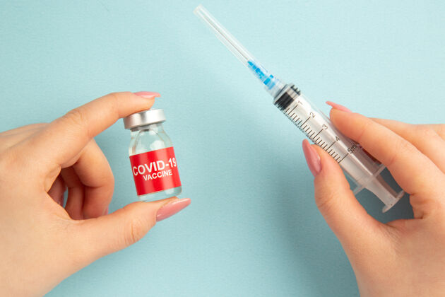 疫苗顶视图covid-疫苗在女性手上注射 蓝色背景大流行实验室covid-科学医院病毒健康颜色设备注射剂病毒