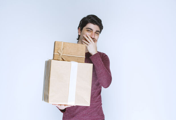 年轻拿着两个纸板礼盒的男人微笑着服装庆祝人