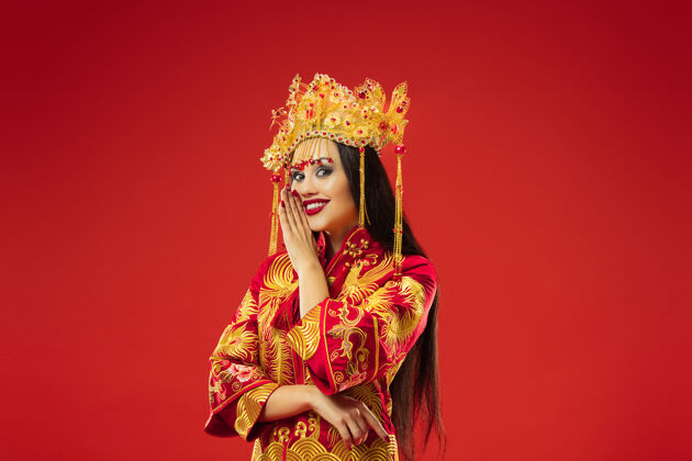 传统中国传统的优雅女子在摄影棚的红色背景美丽的女孩穿着民族服装中国新年 优雅 优雅 表演者 表演 舞蹈 女演员 服装的概念舞蹈女演员亚洲人