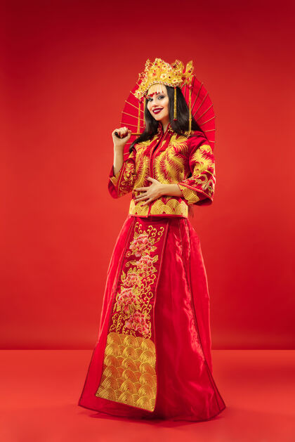 服饰中国传统的优雅女子在摄影棚的红色背景美丽的女孩穿着民族服装中国新年 优雅 优雅 表演者 表演 舞蹈 女演员 服装的概念服饰脸东方