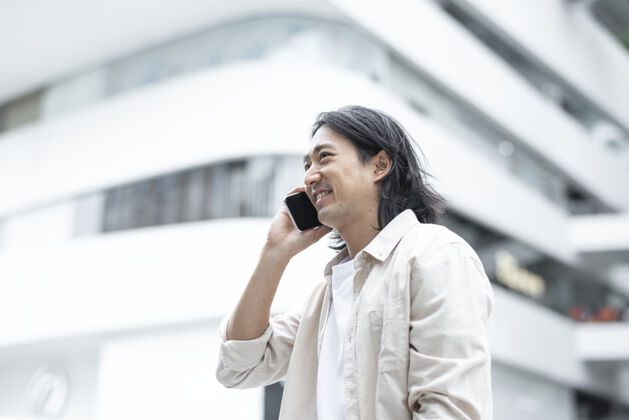 技术快乐的日本男人用他的智能手机说话数字设备聊天移动