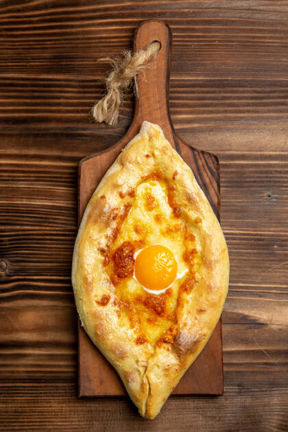 生的顶视图新鲜烤面包与煮熟的鸡蛋在木制表面面包面团面包食品早餐烘焙新鲜早餐