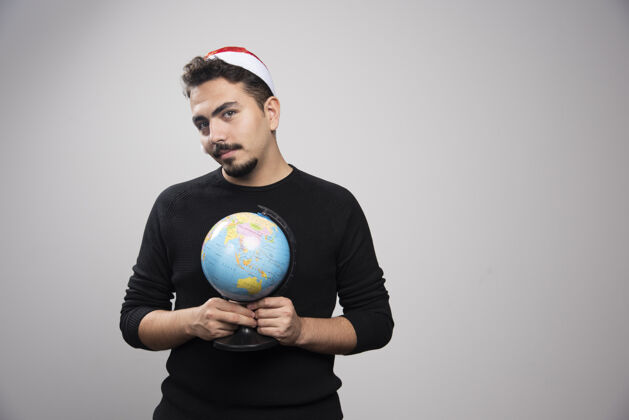 地球戴着圣诞老人帽子拿着地球仪的年轻人帅气男孩地图
