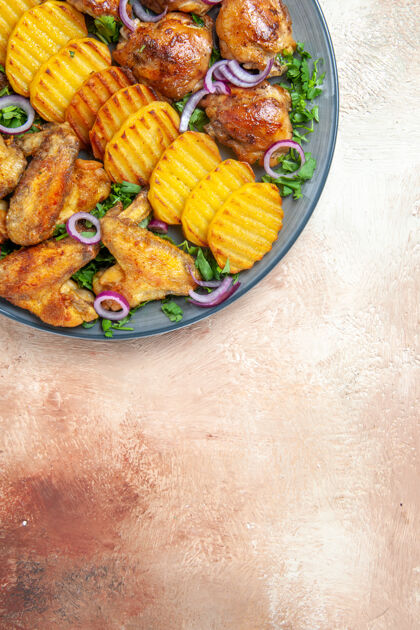 顶部鸡翅俯视图一个开胃的炸鸡土豆药草和洋葱在盘子里一餐肉土豆