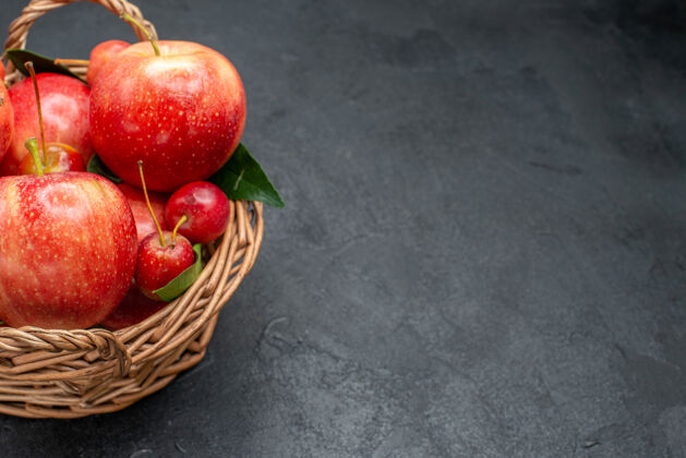 草莓侧面特写查看水果樱桃和苹果的叶子在篮子里放在桌子上成熟樱桃壁板