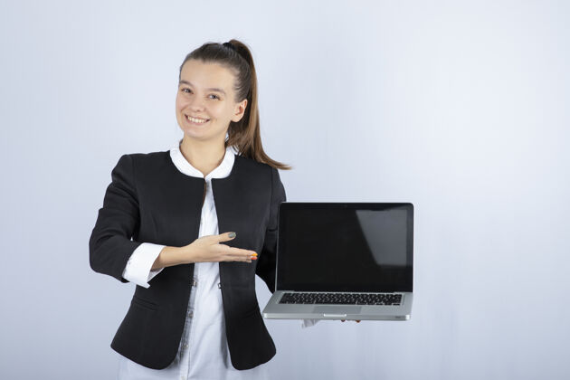 女人在白墙上举着笔记本电脑的年轻女子的画像年轻站立个人
