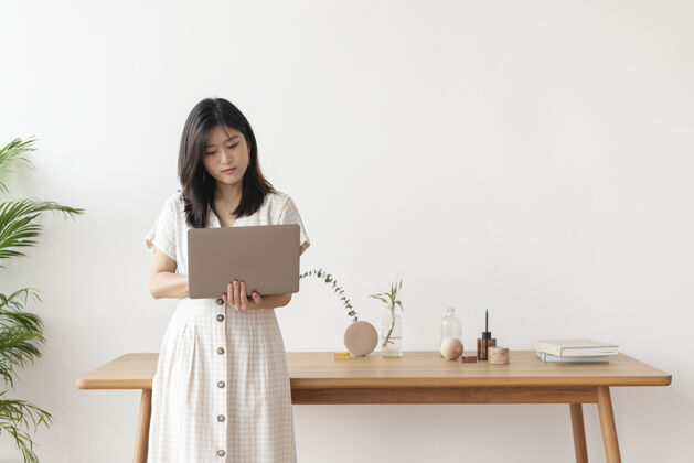 花瓶亚洲女人站在木桌旁用笔记本电脑女人工作亚洲