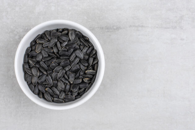 小吃装满向日葵黑籽的碗放在石头上黑烤盐