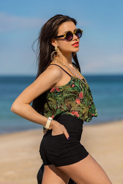 派对时尚女人的夏日肖像 戴着时髦的大饰物和耳环 在海滩上摆姿势放松嘴唇皮肤