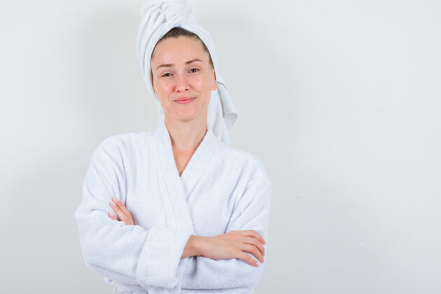 毛巾身穿白色浴袍的年轻女士 双手交叉站在毛巾上 看上去很自信 正面照模特人头发