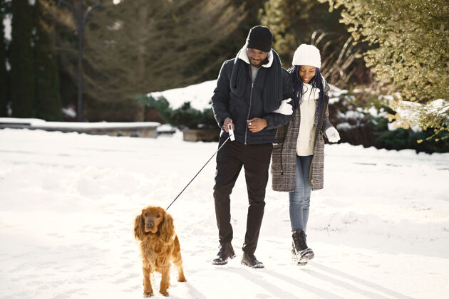 美国人们在外面散步冬天非洲夫妇带着狗乐趣女性公园