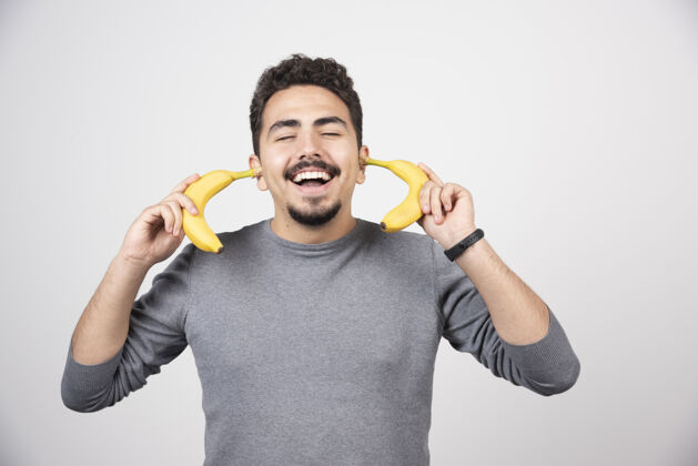 脸一个年轻人拿着两个新鲜的香蕉指点情绪手指