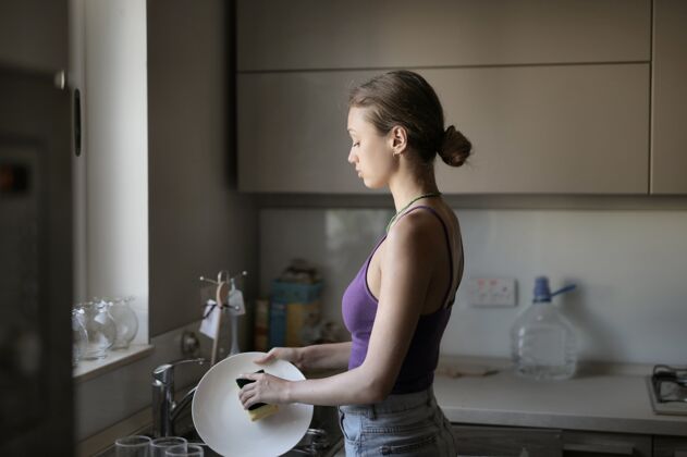 家务年轻的女人在厨房的灯光下洗碗室内房子湿