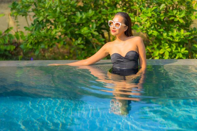 快乐美丽的亚洲年轻女子在游泳池里放松的画像健康成人酒店