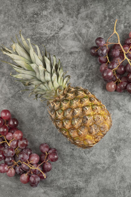 健康新鲜的红葡萄和成熟的菠萝放在大理石表面异国情调自然顶视图