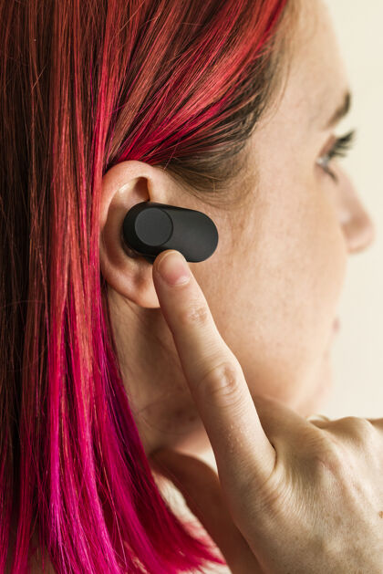 手指戴着无线耳塞的粉红头发女人促销商业耳机
