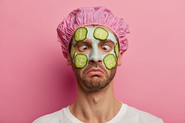 年龄用双目合拢男人的肖像 渴望拥有完美的皮肤 涂上蔬菜面膜和黄瓜 戴上浴帽过程胡茬切片