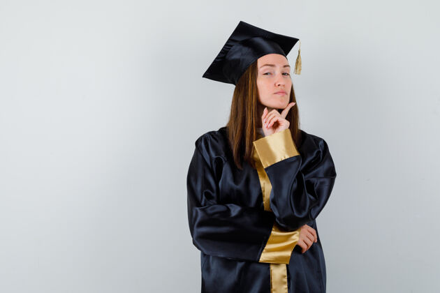 证书女毕业生穿着学院服 用手指托着下巴 看上去很自豪 前视图帽子女性人