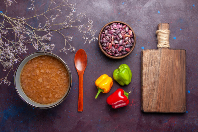 汤顶视图褐色的汤在盘子里用豆子放在深色的表面上汤蔬菜餐食品厨房用油观点晚餐午餐