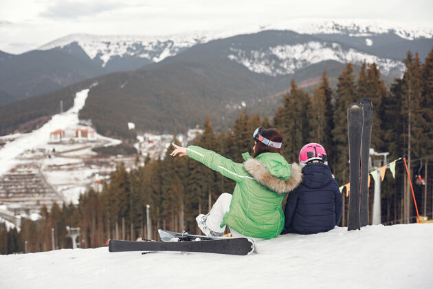 活动妈妈带着女儿在滑雪雪山上的人们头盔肖像雪