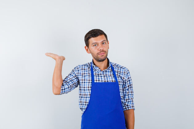 烹饪穿着蓝色围裙和衬衫的年轻男厨师衬衫围裙制服