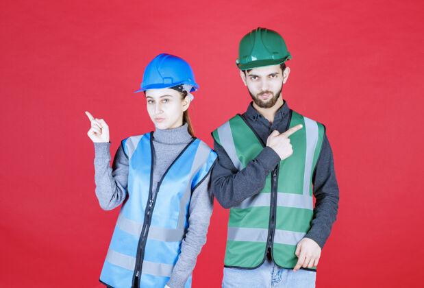 方向男性和女性工程师戴头盔和装备 显示左侧或右侧目的地员工年轻人