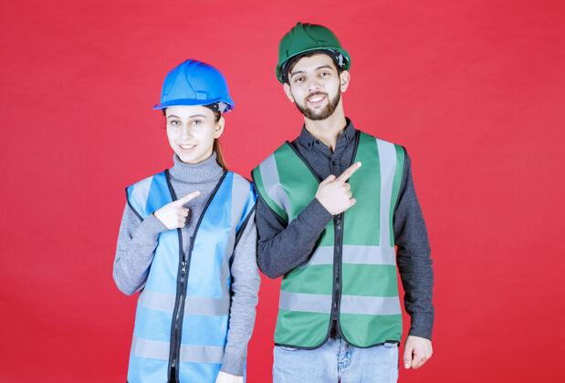 年轻人男 女工程师戴头盔 装备指向右侧施工人姿势
