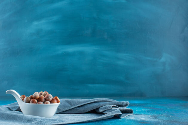 风味把榛子放在勺子里 放在蓝色表面的一块布上毛巾美味坚果