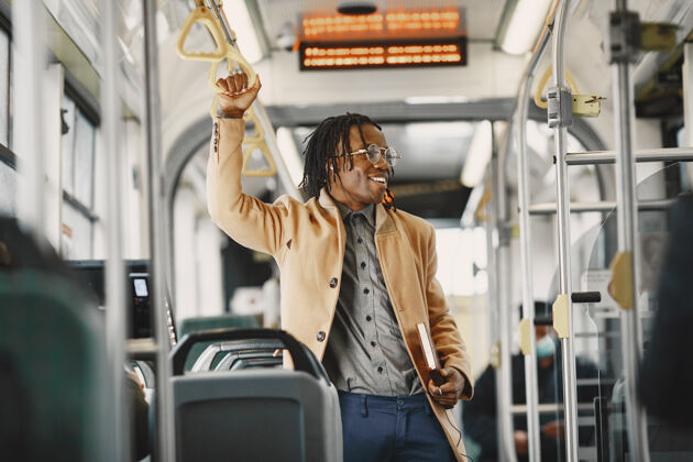 男人一个非洲裔美国人坐在城市公共汽车上一个穿棕色外套的人一个拿着笔记本的人通勤男性车辆