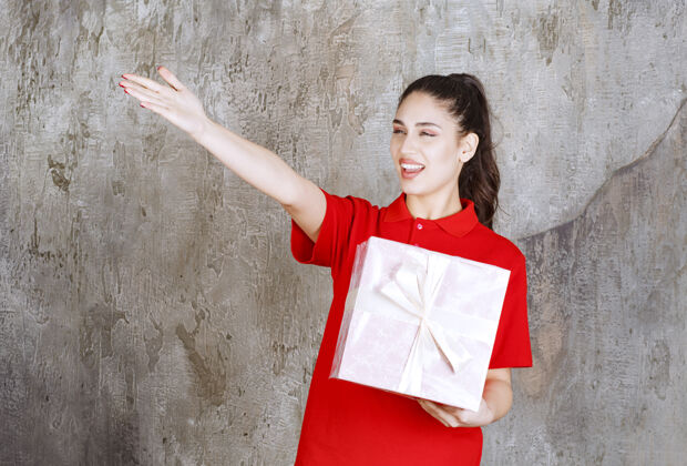 姿势年轻女子拿着一个包着白丝带的粉红色礼盒 指着某人生日通知女人