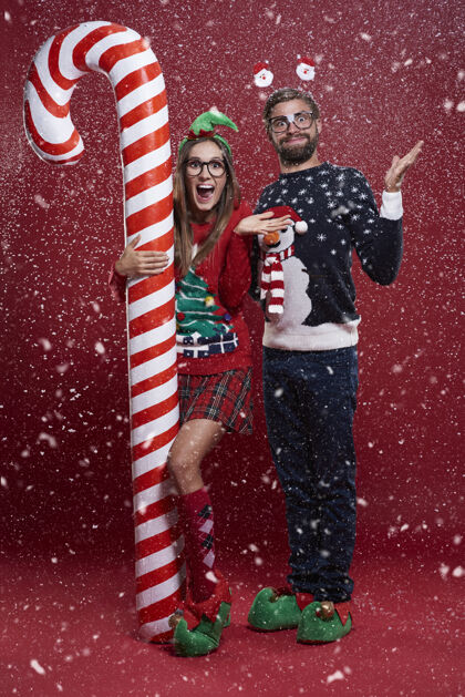 情侣圣诞节的时候 一对夫妇站在糖果手杖旁 雪下得很大极客糖果手杖惊喜