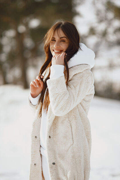 休闲穿黑夹克的女人的特写照片雪天站在森林里的女人寒冷时尚人