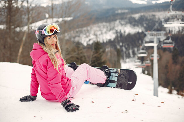 娱乐穿着滑雪板套装的女人在山上手拿滑雪板的运动员在地平线上关于运动的概念板年轻滑雪板