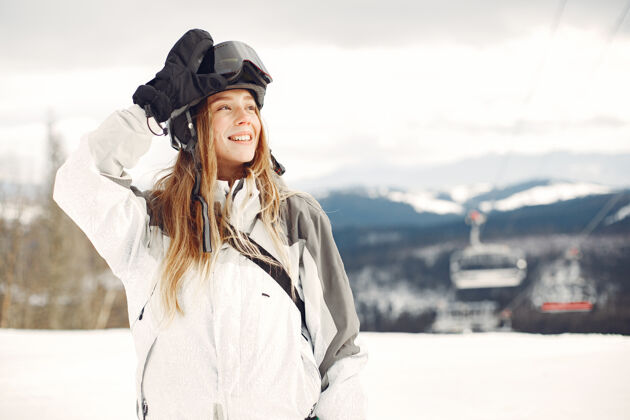 站穿着滑雪板套装的女人在山上手拿滑雪板的运动员在地平线上关于运动的概念滑雪板白娱乐