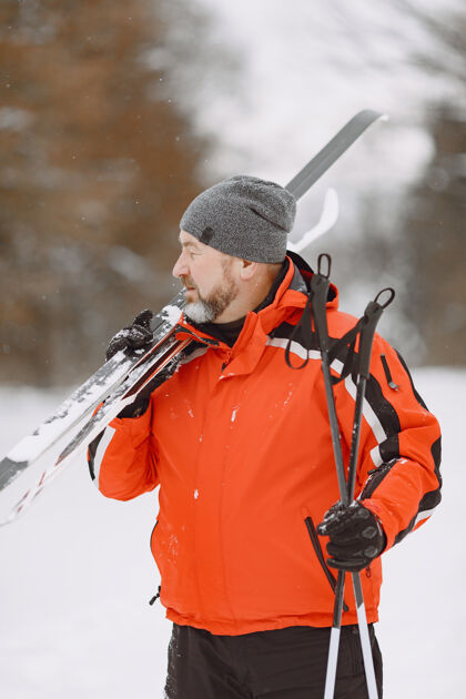 白天冬季公园里快乐的成熟男人高级运动服悠闲地在森林里跋涉雪活跃森林