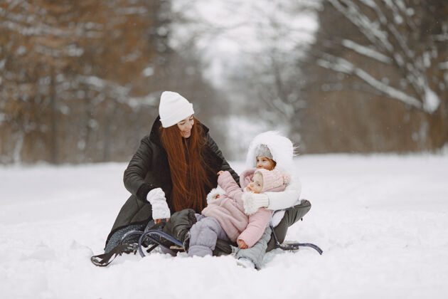 帽子一家人在一起过圣诞节一个公园里的女人和小女孩带着雪橇的人女性户外寒冷