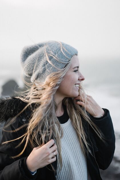 快乐年轻的金发女郎戴着帽子在有风的海滩上玩得很开心海滩沙孤独