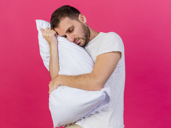头年轻的病人闭着眼睛歪着头 抱着一个粉红色背景的枕头拥抱年轻眼睛