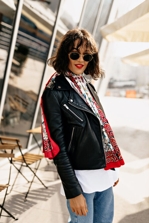 问题时髦的时髦女孩穿着短夹克的皮夹克和红色唇膏在阳光下行走在城市中工作关系商务女性