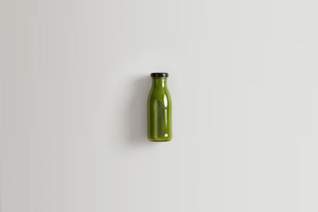 颜色健康的绿色蔬菜冰沙由菠菜 羽衣甘蓝和黄瓜与水混合制成 为您提供适当的营养一瓶白色背景的有机营养饮料稻草新鲜瓶子