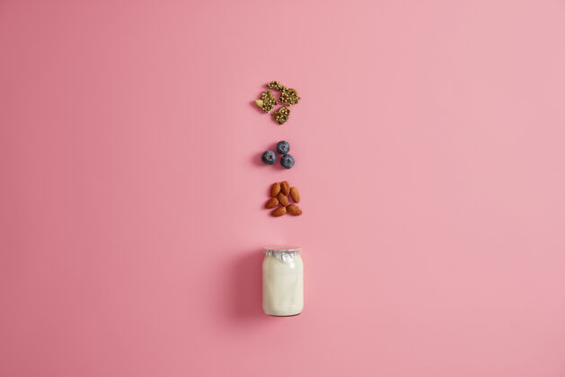 甜点酸奶 南瓜子 蓝莓和杏仁 粉色背景健康营养早餐的原料准备美味的零食均衡的饮食和适当的营养概念配料有机食品牛奶