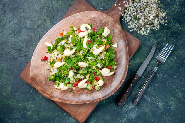 厨房顶视图美味的蔬菜沙拉在盘子里用餐具放在深蓝色的背景上烹饪健康的颜色适合晚餐厨房饮食午餐餐厅盘子午餐餐具