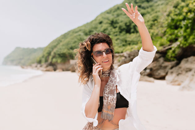 海洋可爱的浪漫女人的画像穿着黑色上衣 白衬衫在智能手机上交谈太阳镜模特成人