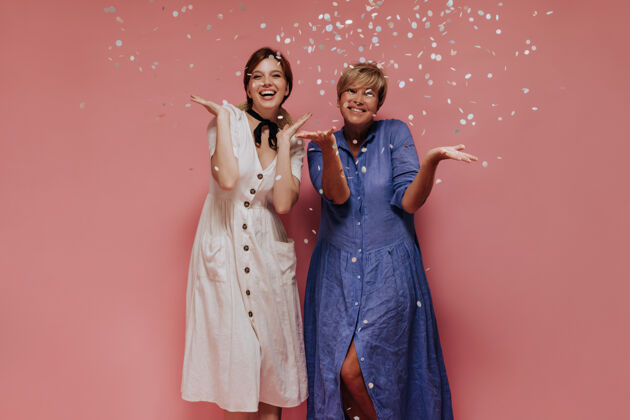 粉色时尚的两位女士 短发 穿着迷笛酷裙 微笑着 在孤立的背景下摆出五彩纸屑的姿势年龄短发肖像