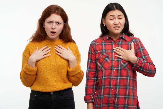 情绪两个年轻的 不快乐的女性朋友困惑 指着怀疑自己人的概念穿黄色毛衣和格子衬衫隔离在白色的墙壁女士毛衣时髦