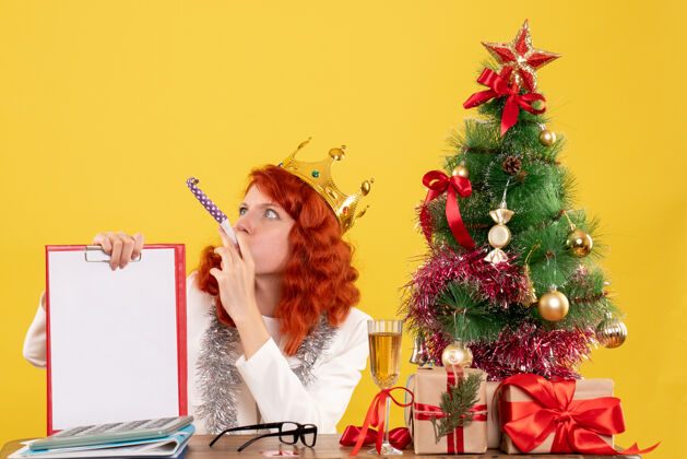 时尚前视图女医生拿着圣诞树周围的文件说明和礼物头发便条节日