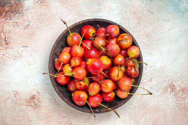 饮食顶部特写查看樱桃一碗红黄色的樱桃放在粉-白-灰的桌子上樱桃有机成熟